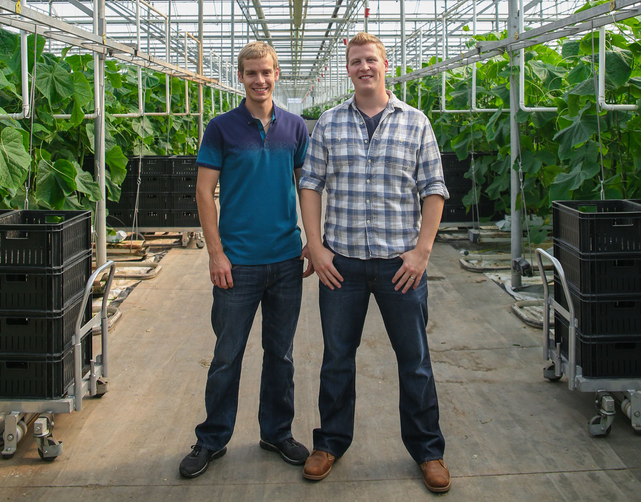 Trevor Voorberg and Chris Voorberg pose for a photo in the greenhouse